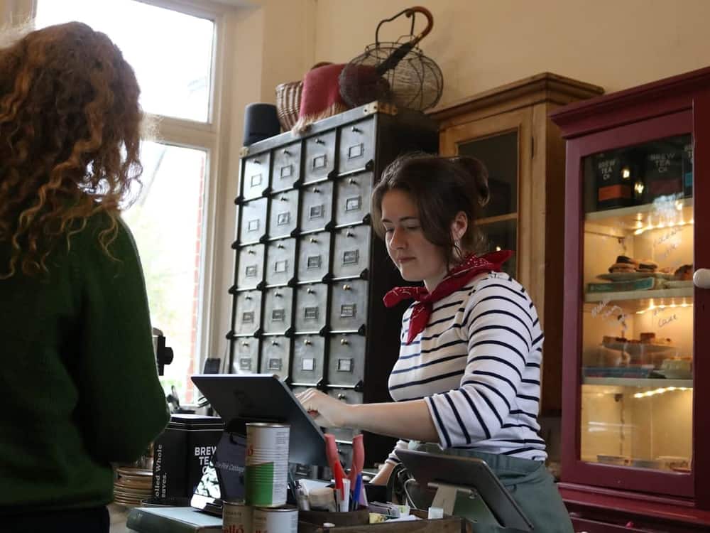 Dependienta atendiendo en el mostrador de una cafetería con un TPV en pantalla